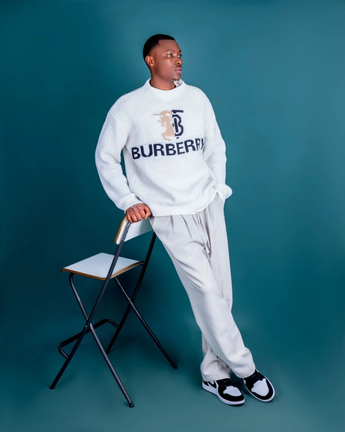 Studio fashion portrait of a man in a white tracksuit on a teal backdrop